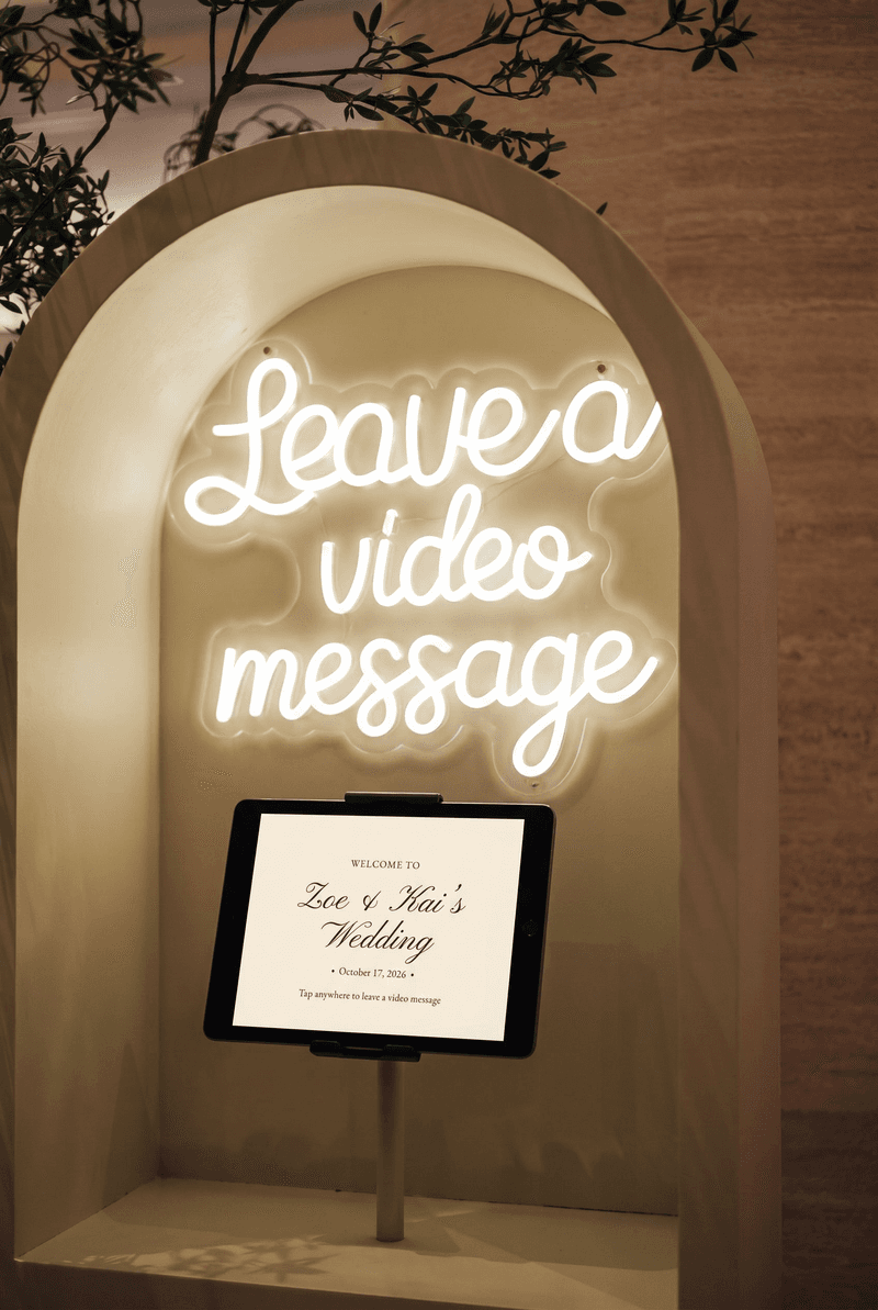 A wedding video guestbook under a neon sign, on an iPad running Votive